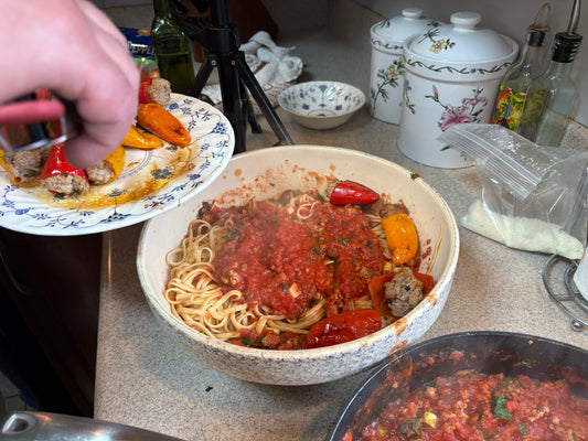 Stuffed mini peppers being added to linguine with tomato sausage gravy